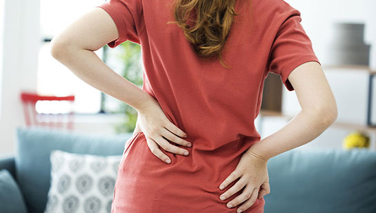 Woman holding lower back in pain before visiting Concord chiropractor