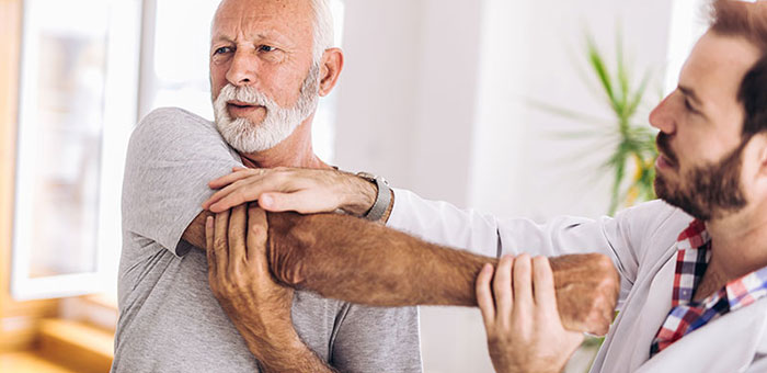 Elderly man receiving shoulder adjustment from Concord chiropractor