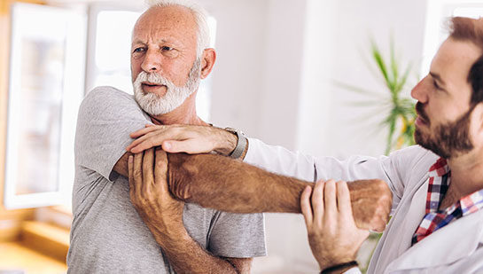 Elderly man receiving shoulder adjustment from Concord chiropractor